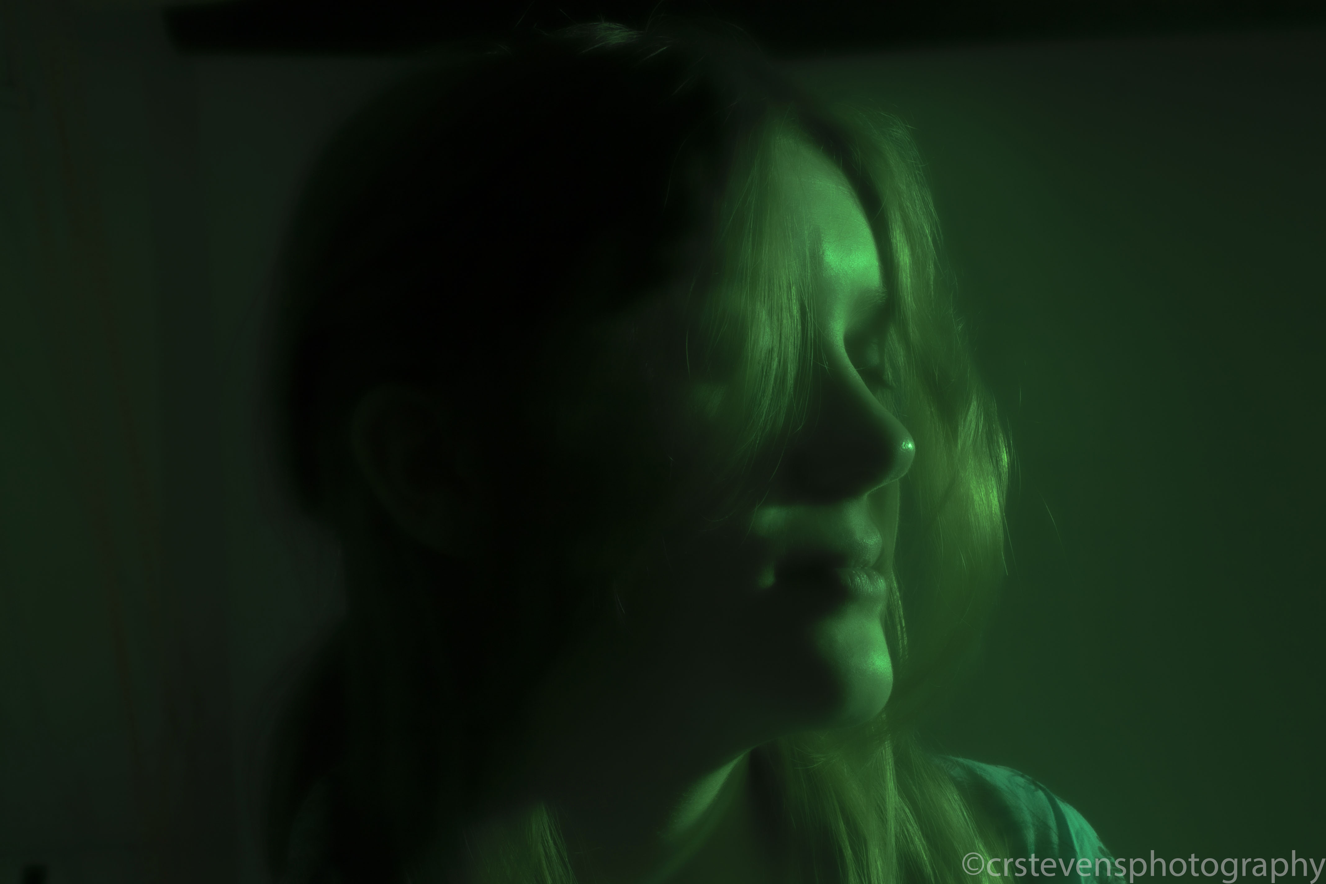 a close up of someones face with their eyes closed and green lighting with a foggy background