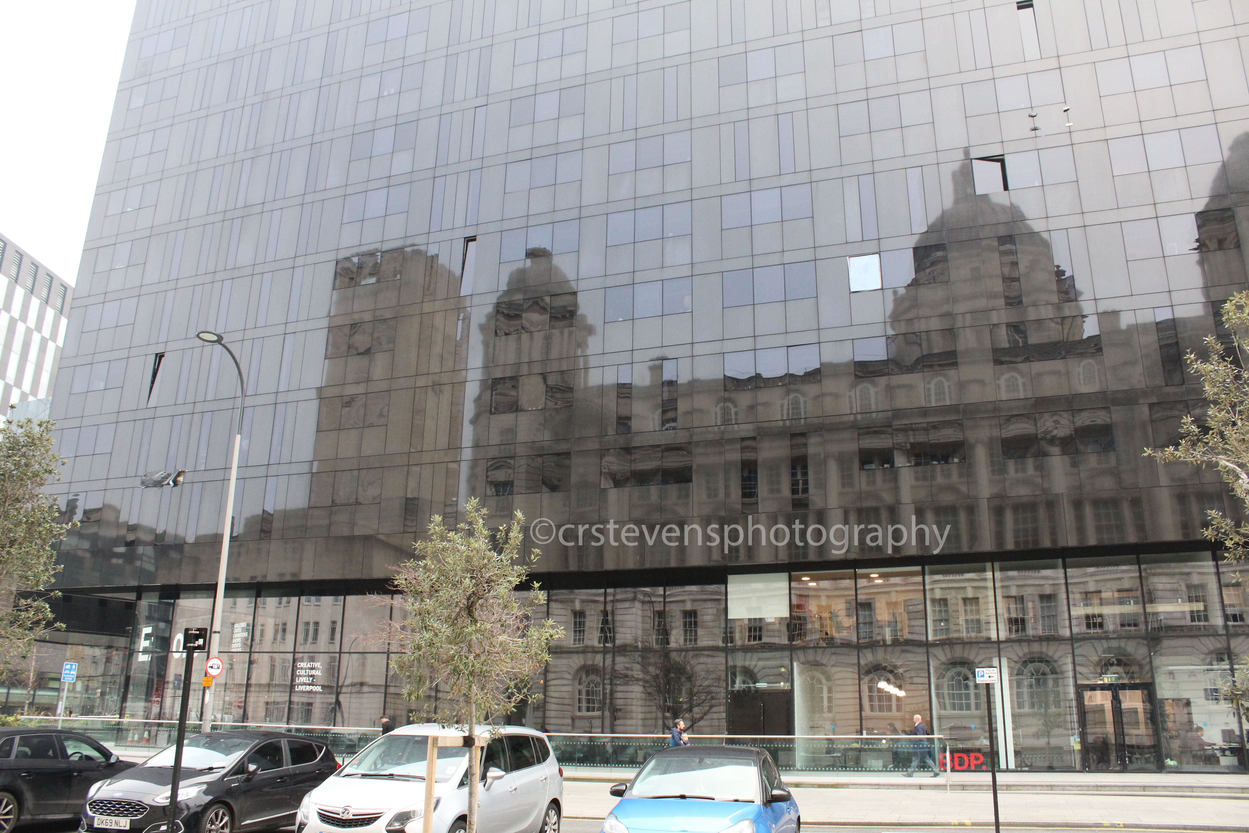 an old building reflected in the glass walls of a modern building